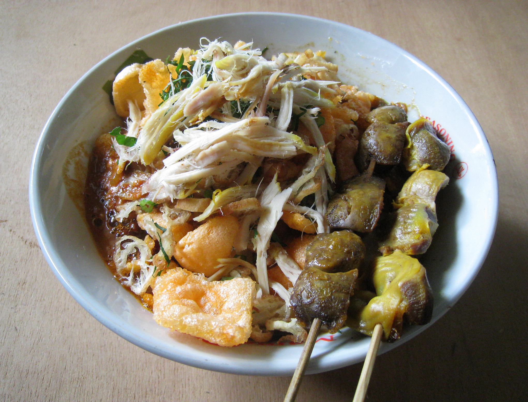 A Bubur Ayam (chicken rice congee) with chicken liver and gizzard satay, sold by travelling vendor cart that frequenting kampung or residential area every morning in Jakarta, Indonesia.